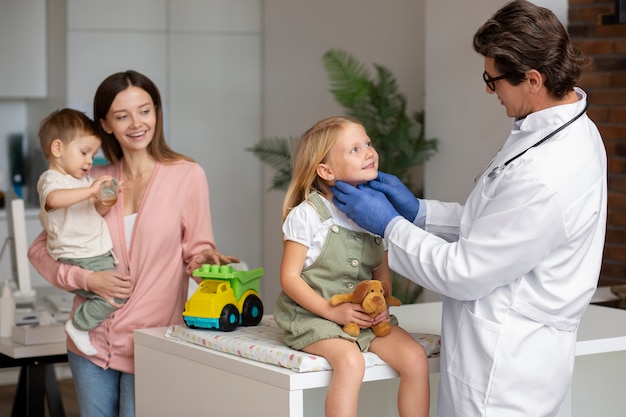 Молодая мать с двумя детьми на приеме у врача