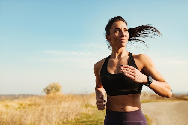 Бесплатное фото Молодая мотивированная спортивная женщина бегает трусцой во время спортивных тренировок на природе