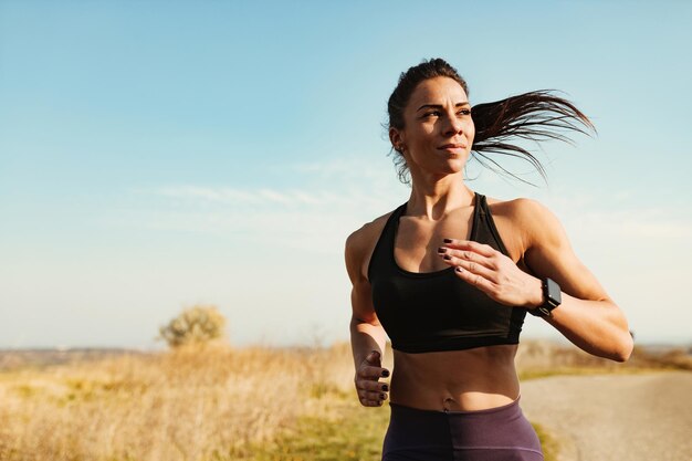 自然の中でのスポーツトレーニング中にジョギングする若いやる気のある運動女性コピースペース