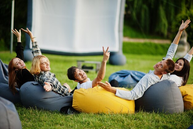 Young multi ethnic group of people watching movie at poof in open air cinema