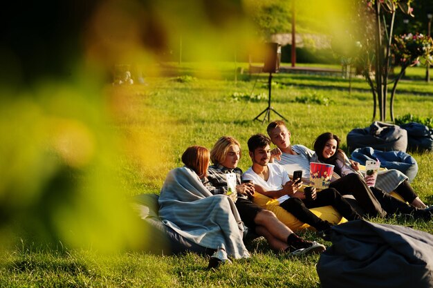 Young multi ethnic group of people watching movie at poof in open air cinema