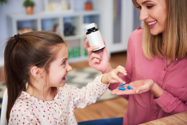 Молодая мама дает своей маленькой дочери лекарство