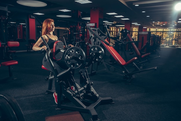 Young muscular caucasian woman practicing in gym with equipment. Wellness, healthy lifestyle, bodybuilding.