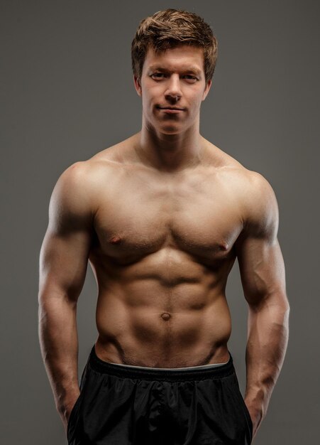 Young muscular guy posing on grey background