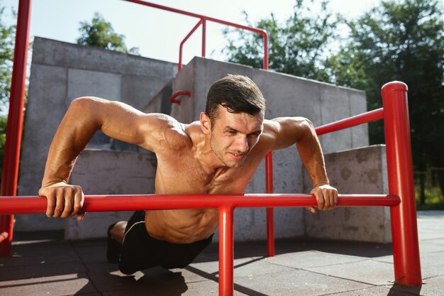 Young muscular shirtless caucasian man doing pull-ups on horizontal bar