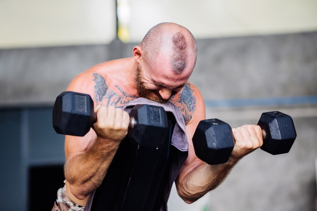 Young muscular tattooed strong muscle bearded european man doing hard exercise