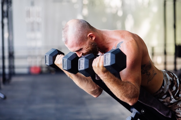 Young muscular tattooed strong muscle bearded european man doing hard exercise