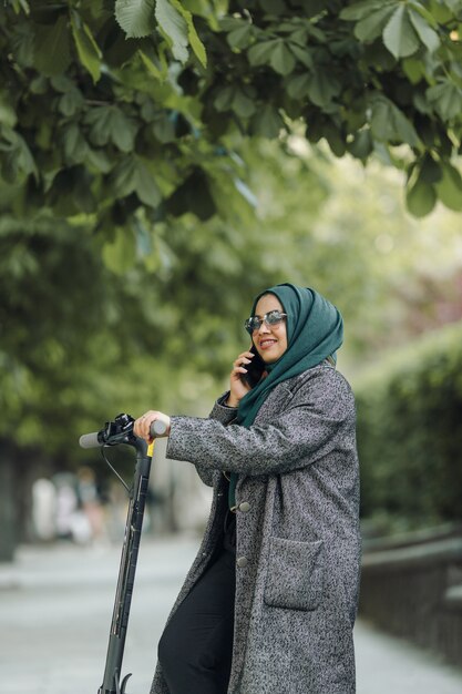 Young muslim woman riding a scooter on a street