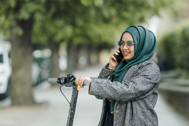 거리에서 스쿠터를 타는 젊은 이슬람 여성
