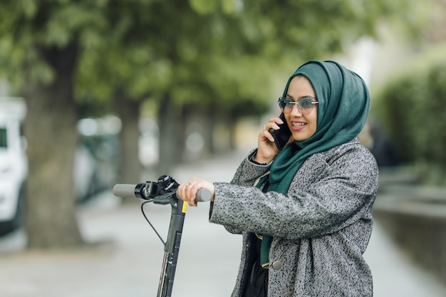 Молодая мусульманка на скутере на улице