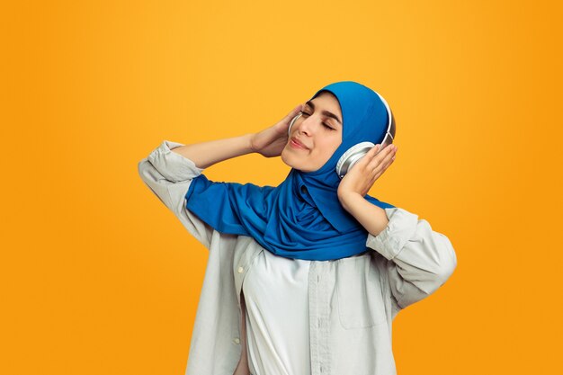 Young muslim woman on yellow background