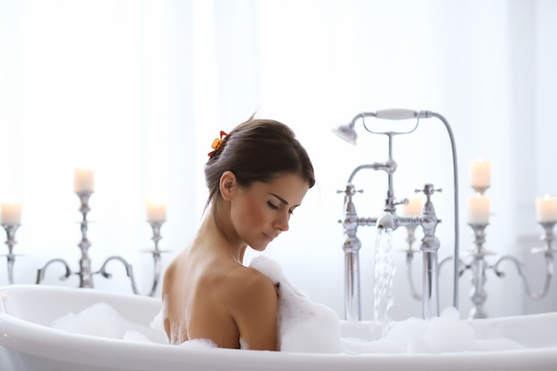 Young nude woman taking a relaxing foamy bath