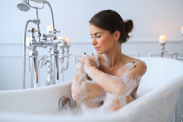 Young nude woman taking a relaxing foamy bath