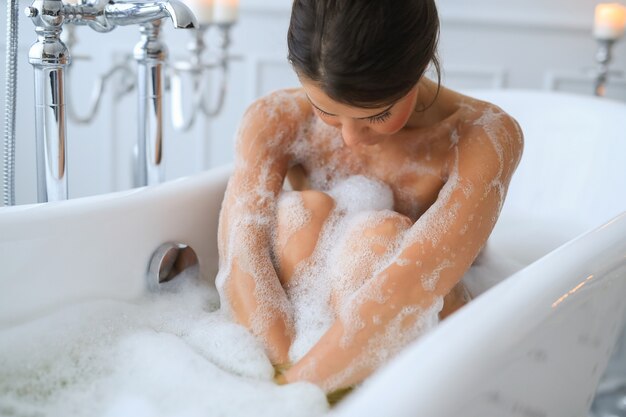 Young nude woman taking a relaxing foamy bath