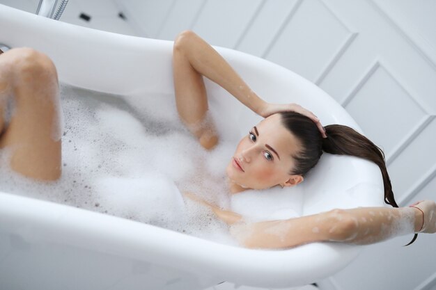 Young nude woman taking a relaxing foamy bath