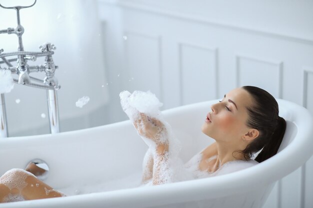 Young nude woman taking a relaxing foamy bath