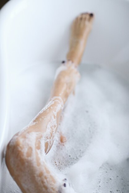 Young nude woman taking a relaxing foamy bath