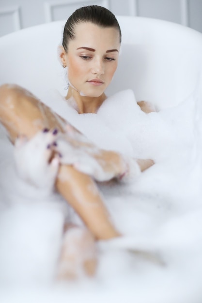 Young nude woman taking a relaxing foamy bath