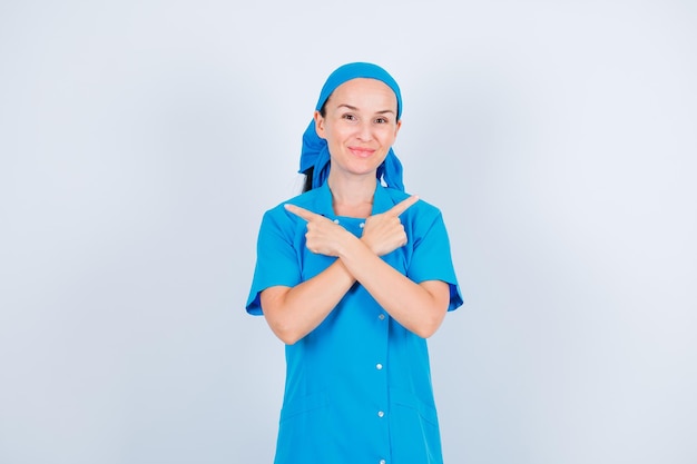 Free photo young nurse is pointing right and left with forefingers on white background