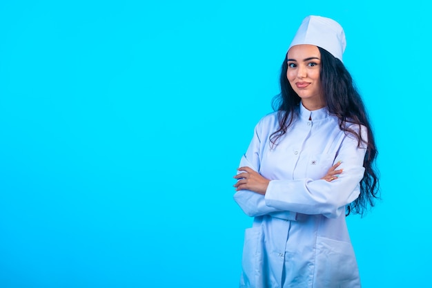 Young nurse in isolated uniform closes arms and smiles