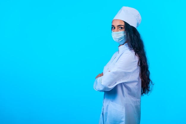 Young nurse in isolated uniform holding closing hands and looks self confident. 