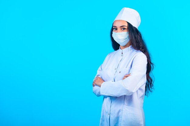 Young nurse in isolated uniform holding closing hands and making confident view