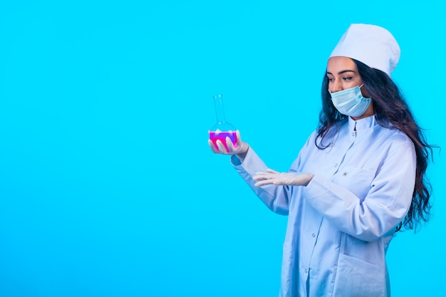 Foto gratuita giovane infermiera in uniforme isolata che tiene una boccetta della prova e la descrive