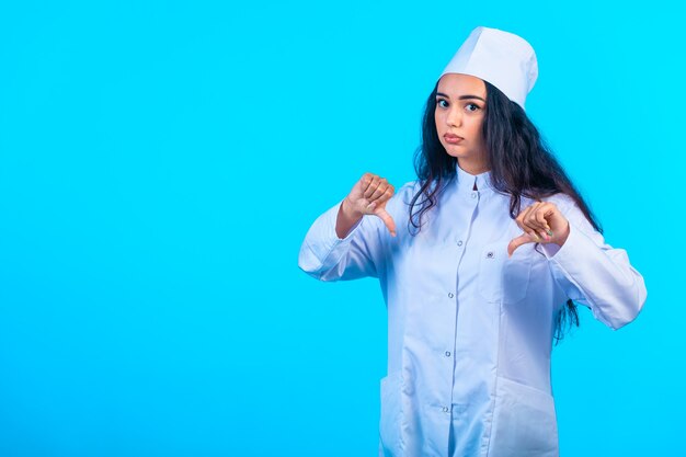 Young nurse in isolated uniform looks depressed and makes negative sign. 