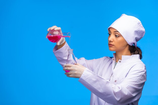 Young nurse puts chemical liquid from one flask to another.