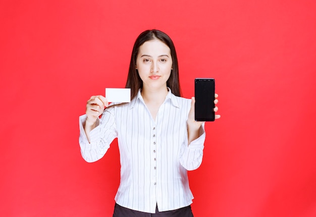 Young office employee showing business card and cellphone. 