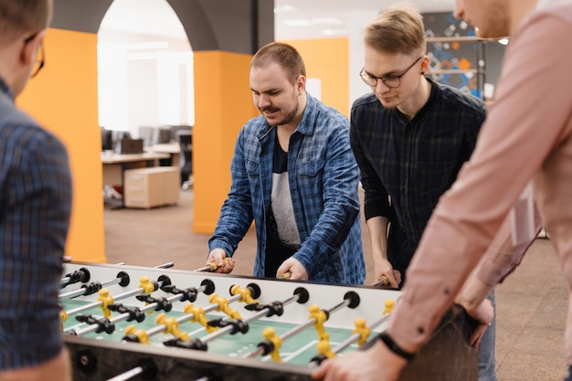 Free photo young office workers playing table soccer