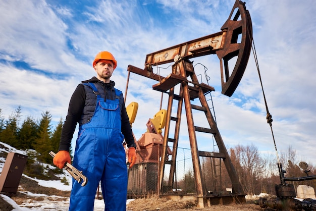 Young oil man standing in front of pump jack