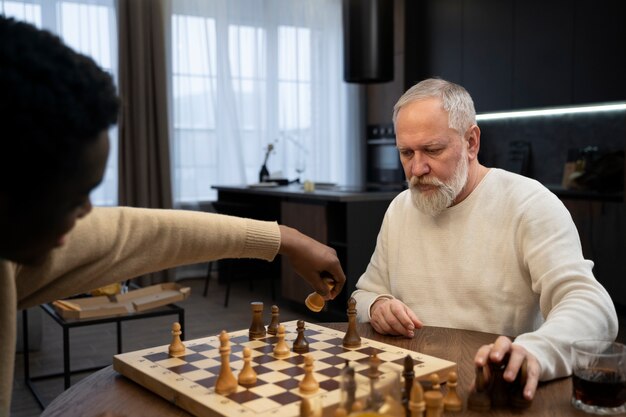 Young and old men playing chess side view