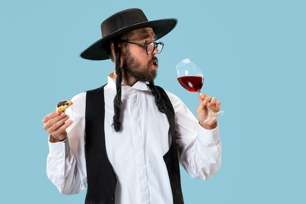 The young orthodox Jewish man with black hat with Hamantaschen cookies for Jewish festival of Purim