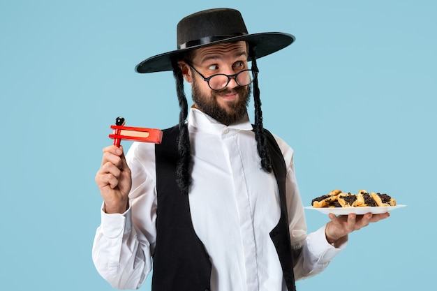 The young orthodox jewish man with hamantaschen cookies for festival Purim