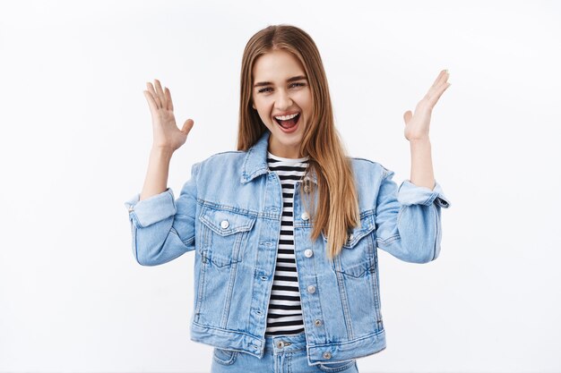 Young overwhelmed and surprised happy blond girl celebrating great news, shaking hands up and smiling broadly, winning competition, achieve prize, triumphing from overjoy and cheer