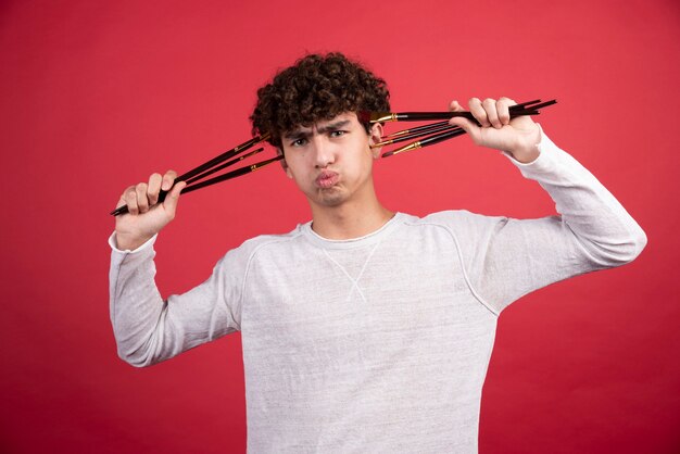 Young painter angrily holding brushes  .