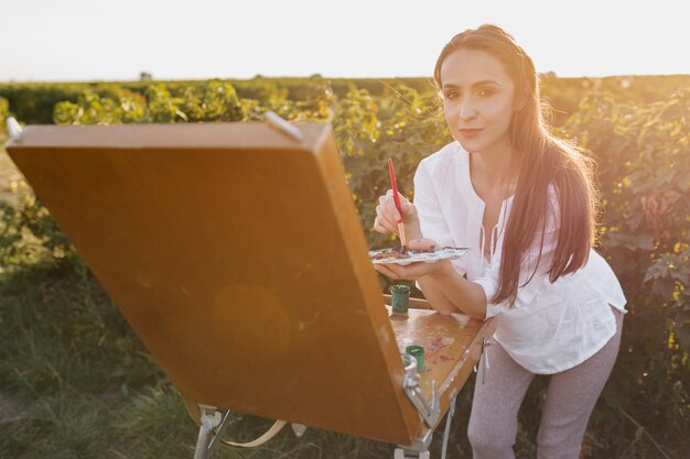 Young painter in the nature looking at camera