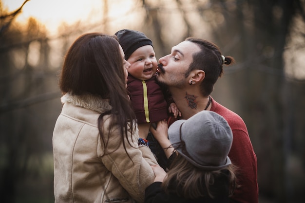 포즈를 취하는 동안 아기를 키스하는 젊은 부모
