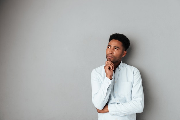 Young pensive african man looking away at copy space