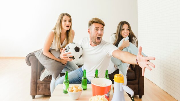 Young people on couch watching soccer game 