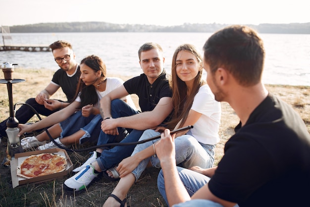 Young people eating pizza and smoking shisha at the beach