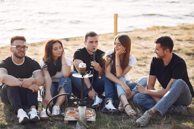 Young people eating pizza and smoking shisha at the beach