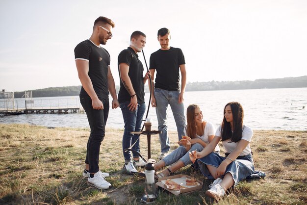 Young people eating pizza and smoking shisha at the beach