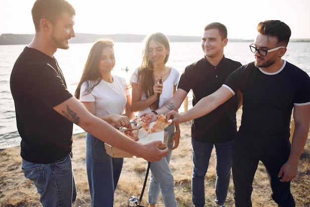 Foto gratuita giovani che mangiano pizza e che fumano shisha sulla spiaggia