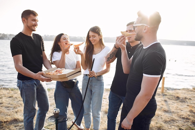 Young people eating pizza and smoking shisha at the beach