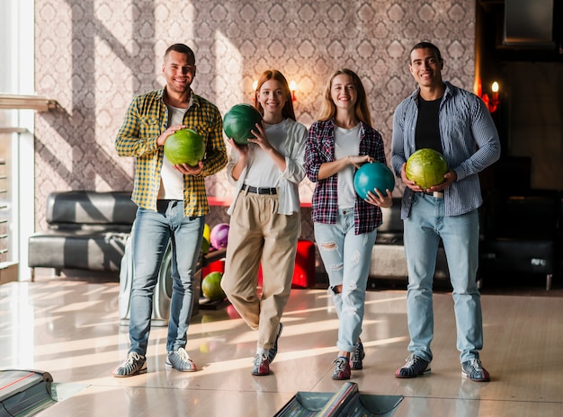 Giovani che tengono le palle da bowling variopinte in un club di bowling