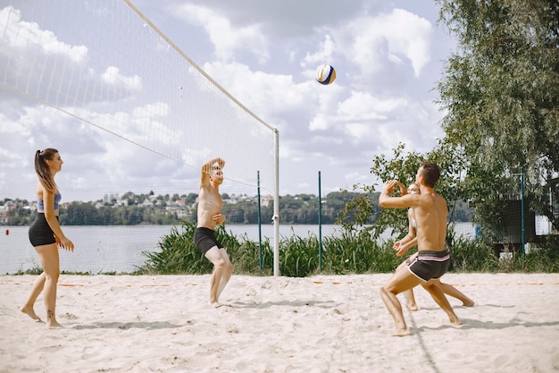 Молодые люди играют в волейбол на пляже