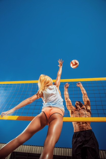 A young people playing volleyball on the beach.