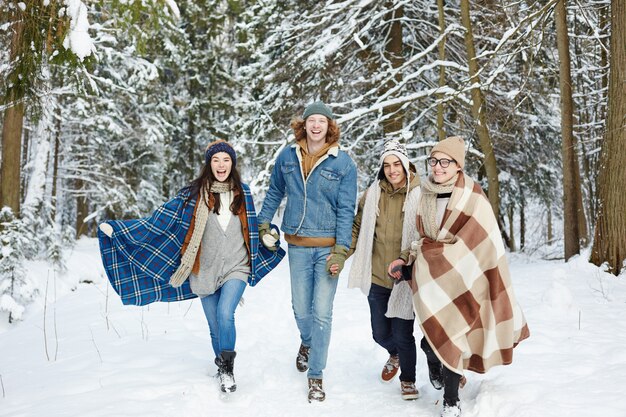 Молодые люди бегут в зимнем лесу